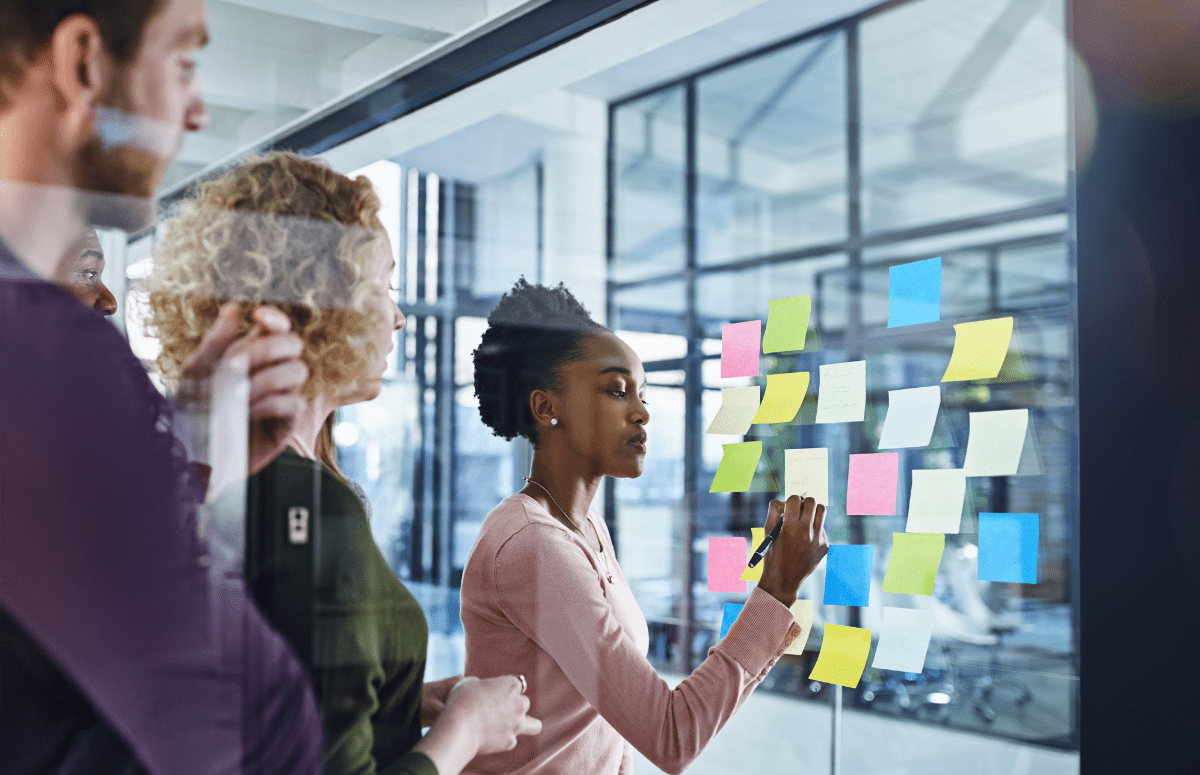 3 people in an office writing on postit notes